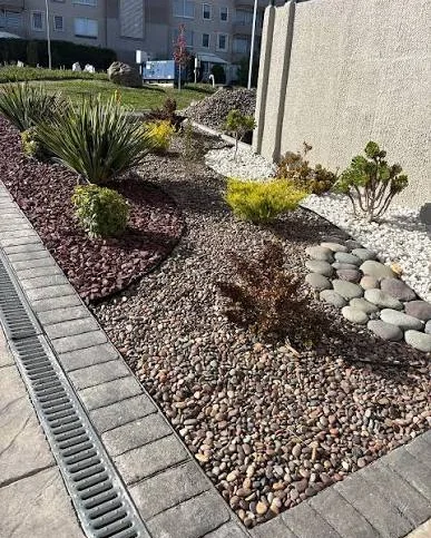 Pebble and gravel bed along a paver walkway with a drainage channel